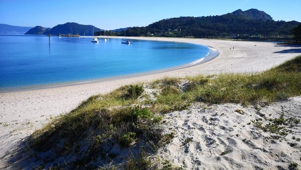 A beach with clear blue water, boats, and mountains in the background. - Villa with Private Pool, Mountain Views & Wi-Fi in Pantón, Ribeira Sacra (Pantón)