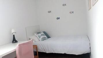 Una habitación pequeña y bien iluminada con una cama, un escritorio y una silla.