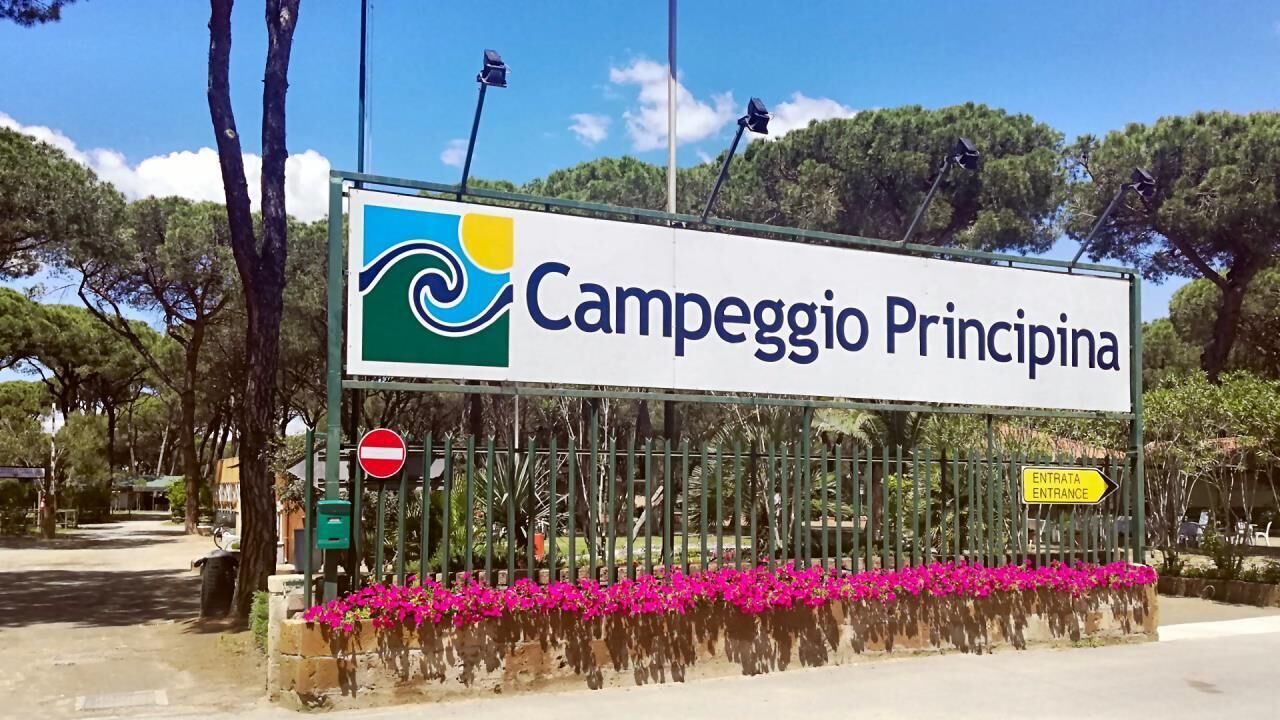Señalización de 'Campeggio Principina' con un cartel de prohibido el paso y un indicador de dirección de entrada.