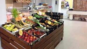 Exhibición de frutas y verduras en una tienda, con una variedad de productos como manzanas, plátanos y hojas verdes.