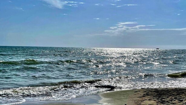 Una playa con olas y un cielo despejado.