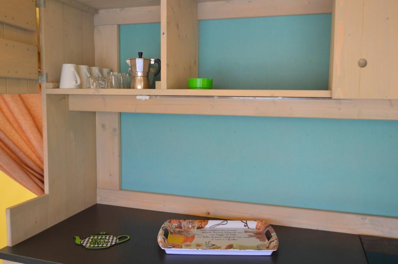 A kitchen area with wooden cabinets, a coffee maker, a green bowl, and a teapot on the countertop.