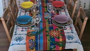 A dining table set with plates, glasses, and a colorful tablecloth.