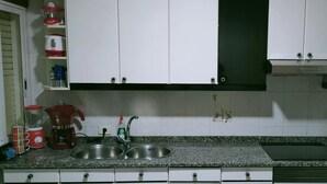 A kitchen with white cabinets, a granite countertop, a sink, a coffee maker, a microwave, and a blender.