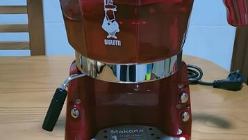 A red coffee machine with a logo, a control panel, and several coffee capsules on a wooden table.
