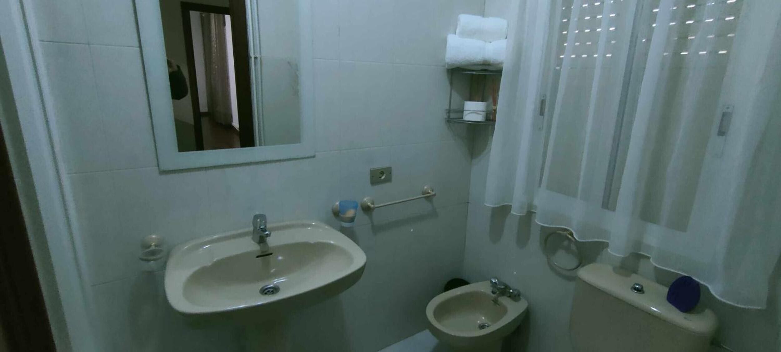 Un bagno piccolo con lavandino, bidet, WC e uno specchio.