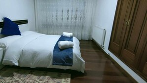 A bedroom with a bed, a nightstand, a wardrobe, and a patterned rug.