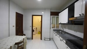 A compact kitchen with white cabinets, a black countertop, and a dining area with a table and chairs.