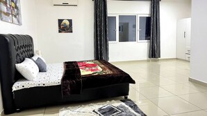Un dormitorio con cama, ventana, cortinas, aire acondicionado y un cuadro en la pared.