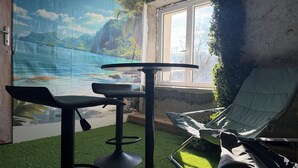 Habitación con un mural de playa tropical, una ventana con vistas, un taburete de bar y una silla de lounge.