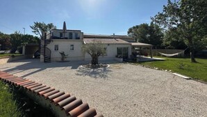 Una casa de dos pisos con camino de grava, un pequeño jardín y un porche cubierto.