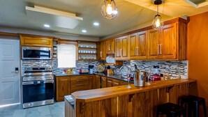 A modern kitchen with wooden cabinets, stainless steel appliances, and a central island. - The Crown Point Escape Villa (Crown Point)