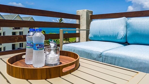 A wooden deck with a round wooden tray holding two bottles of water and a glass. - The Crown Point Escape Villa (Crown Point)