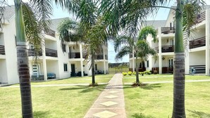 A pathway leading to a multi-story building with balconies, surrounded by palm trees and well-maintained grass. - The Crown Point Escape Villa (Crown Point)