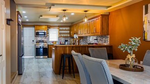 A modern kitchen with wooden cabinets, stainless steel appliances, and a central island. - The Crown Point Escape Villa (Crown Point)
