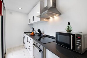 Une cuisine moderne équipée d’un four à micro-ondes, d’un four traditionnel et de meubles en acier inoxydable.