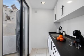 A compact kitchen with a black countertop, a washing machine, and a window overlooking a building.