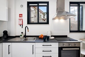 A modern kitchen with a stainless steel sink, a built-in oven, and a window with a view of a building outside.