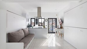 Eine moderne Küche mit Kochinsel, ein Essbereich mit Tisch und Stühlen sowie ein Sofa im Wohnbereich.