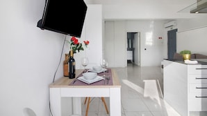 Eine moderne Küche mit Essbereich, einem an der Wand montierten Fernseher und einer Pflanze auf der Arbeitsfläche.