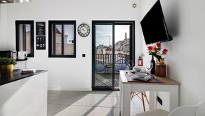 Eine moderne Küche mit schwarzem Arbeitsplatz, einer Kaffeemaschine, einem Topf mit Pflanze und einem Essbereich mit Tisch, Stühlen und einer Vase mit Blumen.