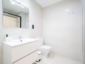 Ein modernes Badezimmer mit Waschbecken, Toilette und Duschbereich in Weiß.