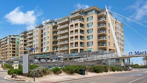 A multi-story hotel with balconies, a pedestrian bridge, and a marina sign.