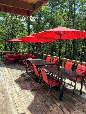 Une terrasse en bois avec des meubles d’extérieur rouges et des parasols.