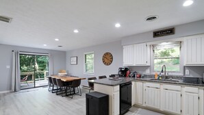 Una cocina moderna con armarios blancos, una mesa de comedor de madera y un reloj en la pared.