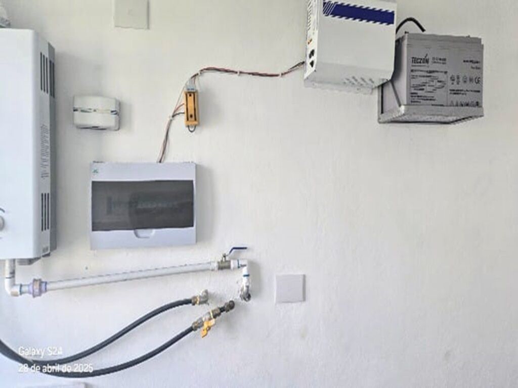 A wall-mounted electrical setup with a white device, a box labeled "TECNON," and a visible wire.