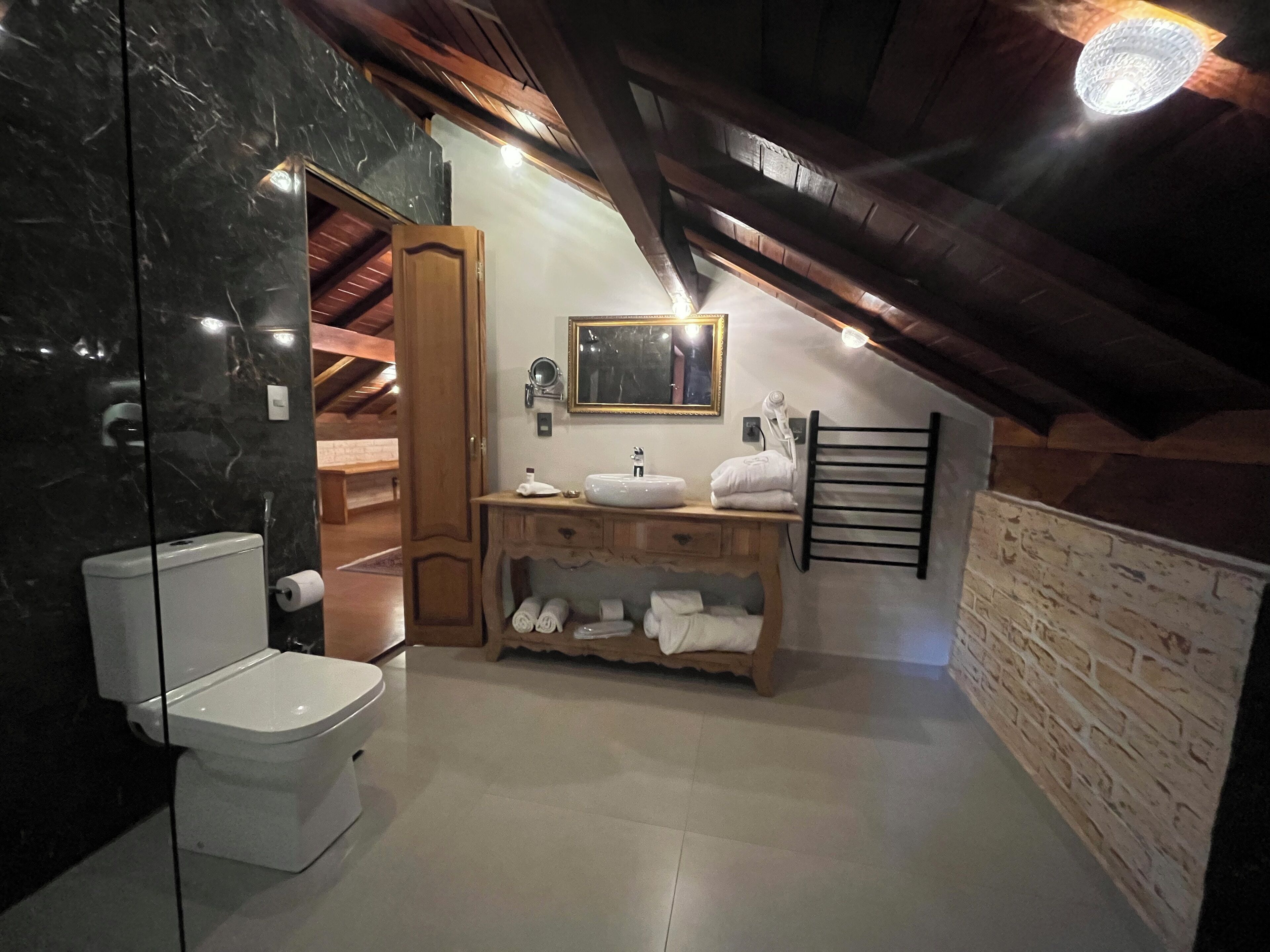 Un baño con inodoro, lavamanos y tocador de madera.