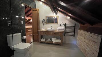 Un baño con inodoro, lavamanos y tocador de madera.