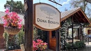 A wooden sign with the name 'Pousada Dona Bendita' hanging above a rustic entrance.