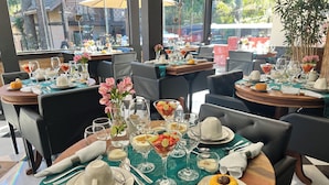 A restaurant setting with tables set for dining, featuring a variety of dishes and drinks.