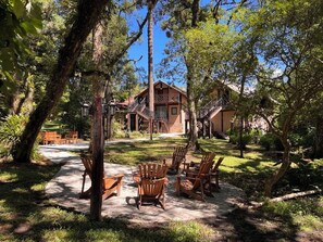 A rustic lodge with a wooden deck, outdoor seating, and a staircase leading to a second-story balcony. - Pousada Dona Bendita (Camanducaia)