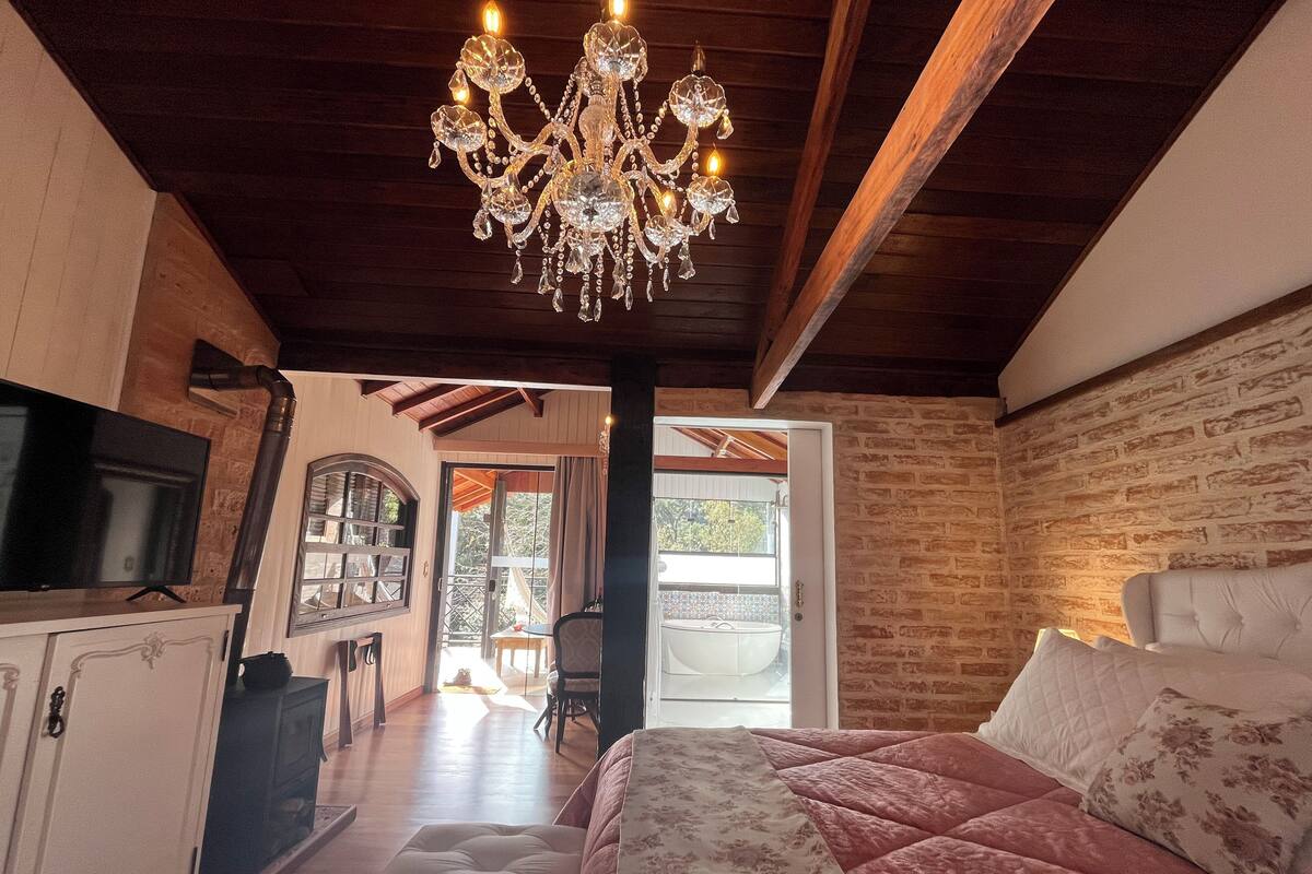 Un dormitorio con una cama grande, un candelabro, un televisor y vistas al exterior.