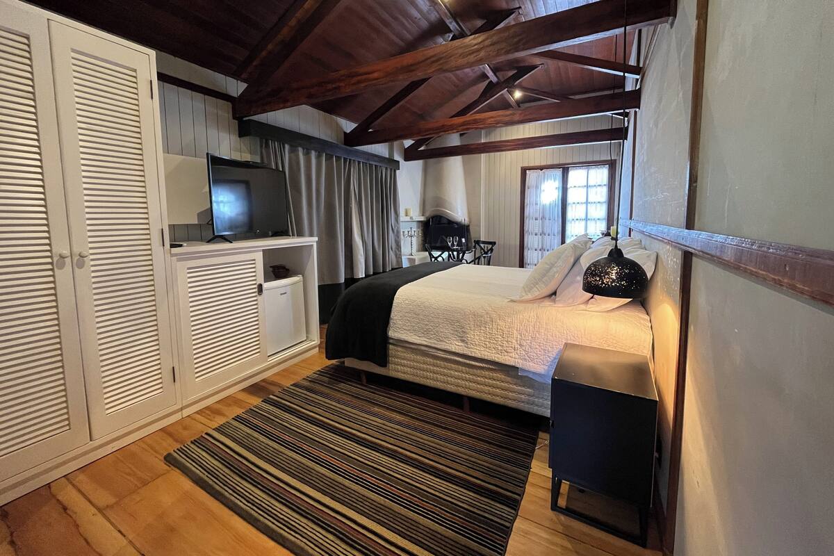 Un dormitorio con una cama, un televisor, un escritorio y una silla.
