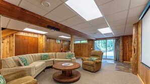 A spacious room with a large sectional sofa, a round wooden coffee table, and a single armchair.