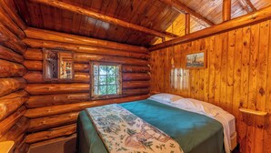 A log cabin room with a bed, a window, and a mirror. - A Charming Lakefront Retreat with Resort Comfort (Orr)