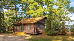 A log cabin with a green door, two windows, and a small porch area. - A Charming Lakefront Retreat with Resort Comfort (Orr)