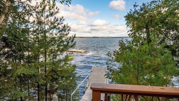 A wooden dock extending over a body of water, surrounded by dense trees. - Spacious Comfort with a Private Dock (Orr)