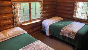 A cabin with two beds, each with a green bedspread and white pillows, and a window with patterned curtains. - Spacious Comfort with a Private Dock (Orr)