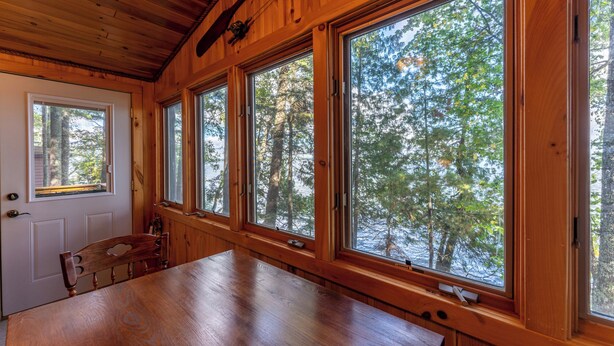 A wooden cabin with large windows offering views of a forest. - Lakefront Cabin with Shared Dock (Orr)