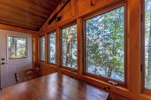 A wooden cabin with large windows offering views of a forest. - Lakefront Cabin with Shared Dock (Orr)