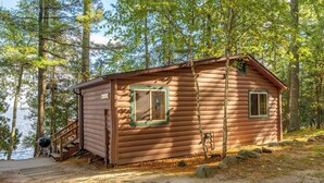 A log cabin with a wooden deck and a small staircase leading to a door. - Lakefront Cabin with Shared Dock (Orr)
