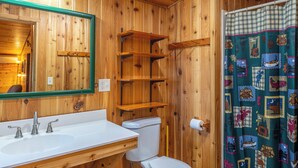 A wooden bathroom with a white sink, a toilet, and a shower curtain with a wildlife pattern. - Vaulted Ceilings and a Stunning Main Room (Pet-Friendly) (Orr)