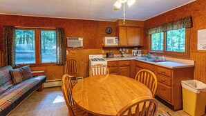 A cozy cabin-style kitchen with wooden cabinets, a dining table, and a ceiling fan. - The Most Private, Pet-Friendly Cabin (New Screened Porch in 2024) (Orr)