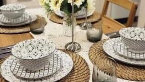 Una mesa de comedor adornada con platos estampados, un florero y candelabros.