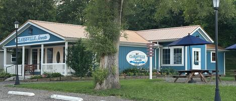 A blue building with a sign reading "Clarksville Sweets" and a picnic table with a blue umbrella.