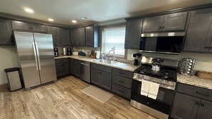A modern kitchen with stainless steel appliances, dark cabinetry, and a granite countertop.